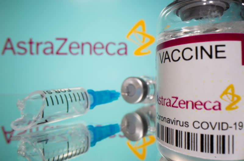 Vial labelled "AstraZeneca COVID-19 Coronavirus Vaccine" and a broken syringe are seen in front of a displayed AstraZeneca logo in this illustration