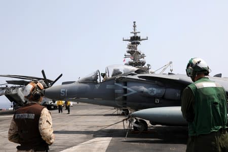 U.S. Marines maintain an AV-8B Harrier aircraft on the flight deck of USS Boxer (LHD-4) in the Arabian Sea off Oman