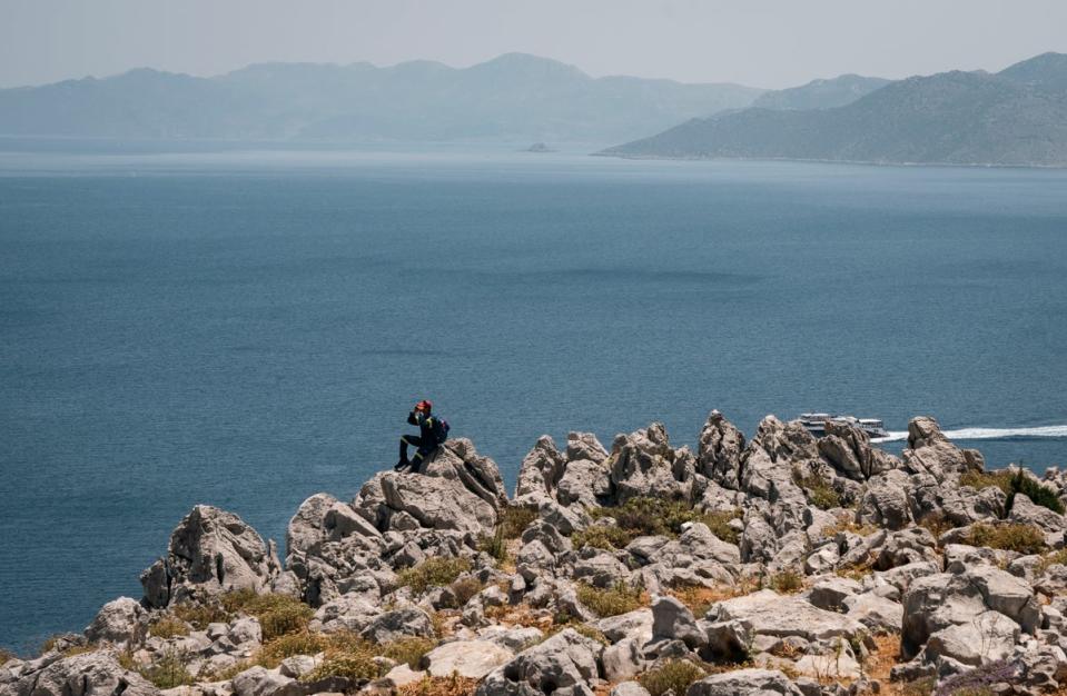 A firefighter sits on a rock during a search and rescue operation for Michael Mosley who was last seen on Wednesday (AFP via Getty)