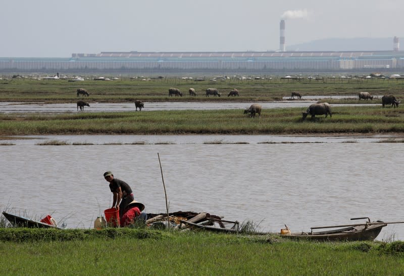 People are seen by a river outside Formosa steel mill in Ha Tinh province