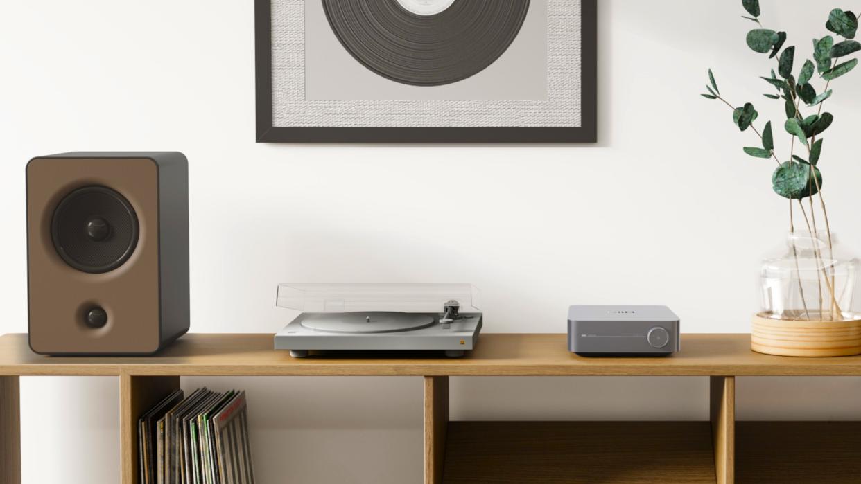  WiiM Amp in lifestyle setting with speaker and turntable on a desktop. 