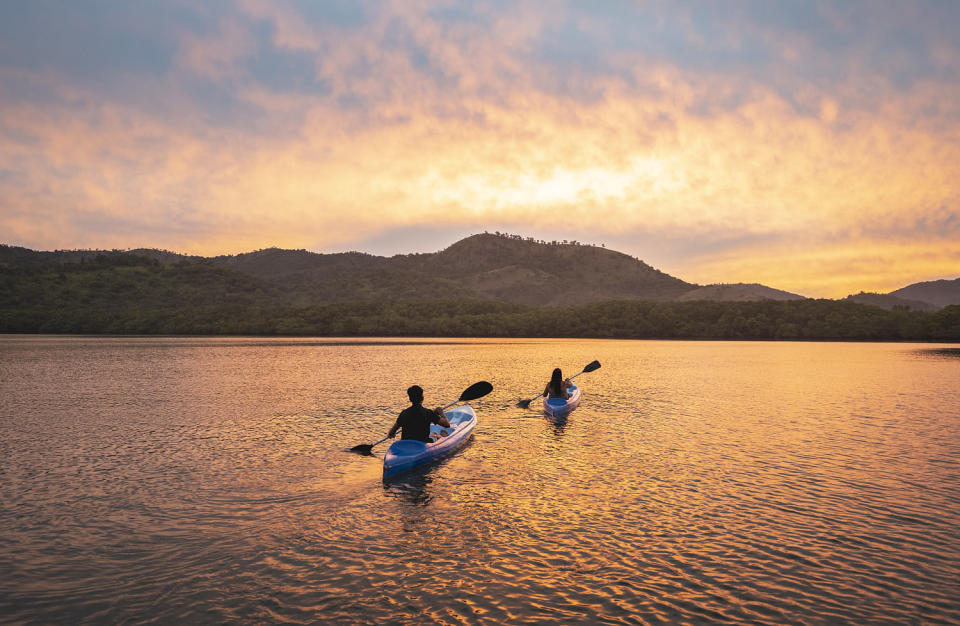 Two people kayaking in a lagoon at sunset. (Marco Bottigelli / Getty Images)