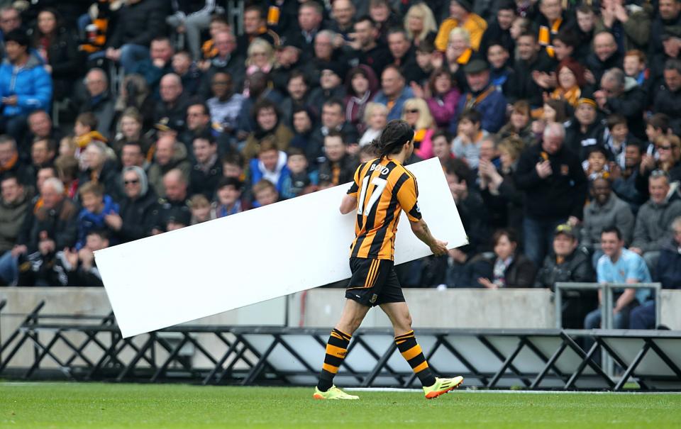 Hull City's George Boyd helps replace the advertising boards after they blow onto the pitch during their English Premier League match against Arsenal at The KC Stadium, Hull, Sunday April 20, 2014. (AP Photo/PA, Lynne Cameron) UNITED KINGDOM OUT NO SALES NO ARCHIVE