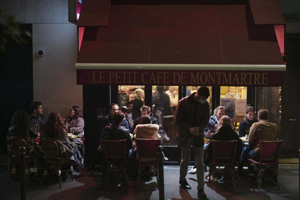 FILE - In this Sept.26, 2020 file photo, people enjoy a drink in a cafe terrace in Paris. French authorities have placed the Paris region on maximum virus alert on Monday, banning festive gatherings and requiring all bars to close but allowing restaurants to remain open, as numbers of infections are rapidly increasing. (AP Photo/Lewis Joly, File)