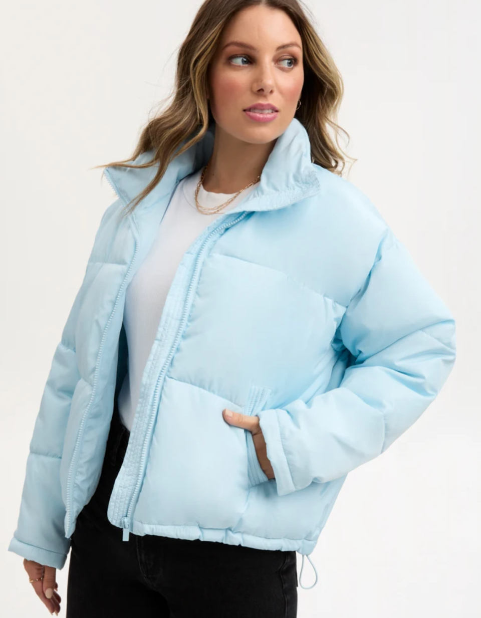 A model wears a baby-blue puffer jacket over white shirt and black pants.