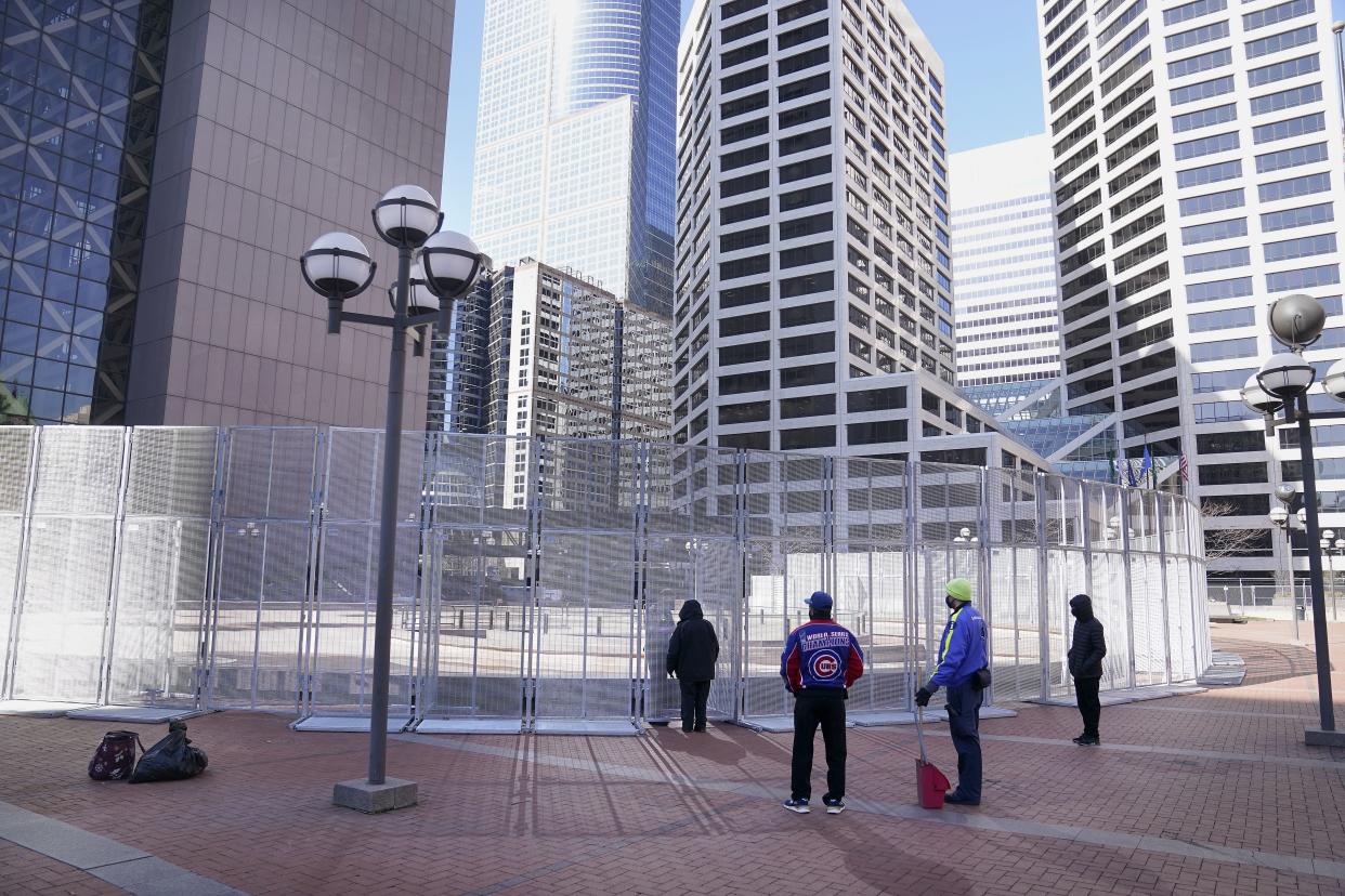 People wait to conduct business outside the Hennepin County Government Center with a law enforcement officer inside a fenced perimeter as preparations continue for the murder trial of former Minneapolis police officer Derek Chauvin, which begins Monday.