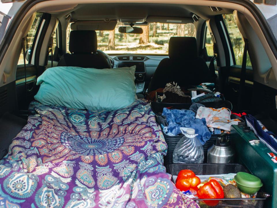 The insider of a car with a bed and lots of miscellaneous belongings