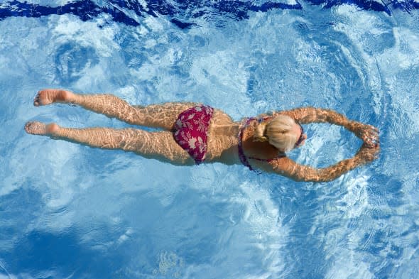 Active mature woman swimming in the pool.