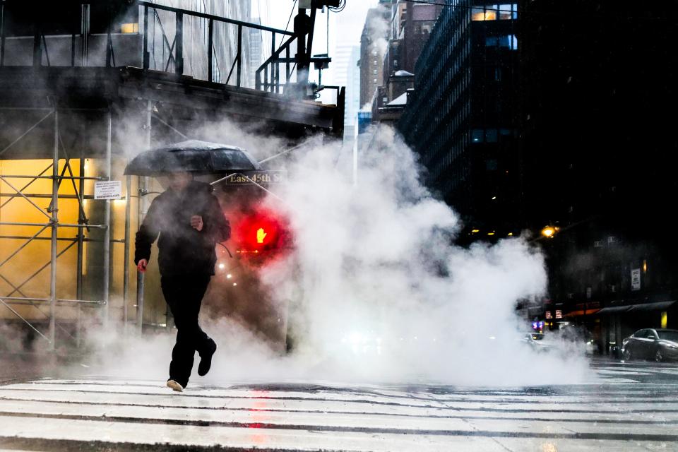 A man crosses a street during heavy rain in the Manhattan borough of New York on March 23 (AFP via Getty Images)