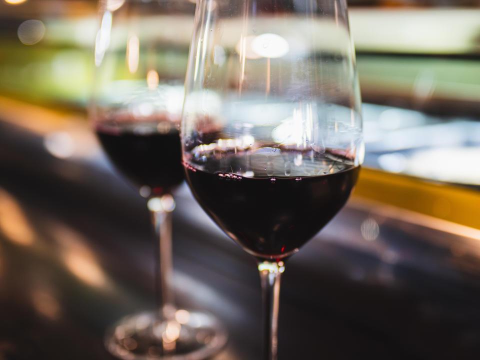 Two glasses of red wine on a table, with a blurry background