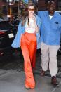 <p>In a baby blue jacket, high-waisted Stella McCartney bright orange pants, retro shades, and a graphic t-shirt while out in New York City. </p>