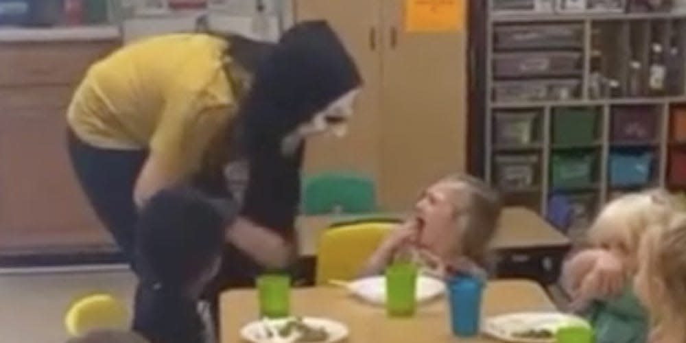woman scaring little girl while wearing a halloween mask