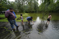 Cal Kingsmill, Jr., and his wife Jessie Kingsmill, point out crickets to their children Marina, 8, and Raylan, 8, in the receding floodwater in front of their home, after Tropical Storm Claudette passed through, in Slidell, La., Saturday, June 19, 2021. The National Hurricane Center declared Claudette organized enough to qualify as a named storm early Saturday, well after the storm's center of circulation had come ashore southwest of New Orleans. (AP Photo/Gerald Herbert)