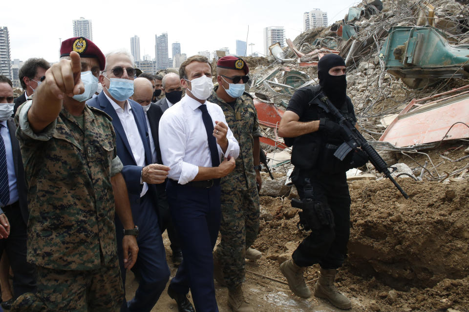 French President Emmanuel Macron, center, visits the devastated site of the explosion at the port of Beirut, Lebanon, Thursday Aug.6, 2020. French President Emmanuel Macron has arrived in Beirut to offer French support to Lebanon after the deadly port blast. (AP Photo/Thibault Camus, Pool)