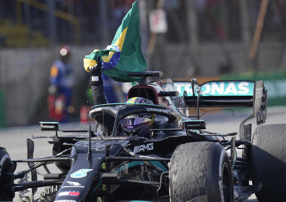 Mercedes' Lewis Hamilton holds a Brazilian flag as he celebrates wining the Brazilian Formula One Grand Prix at the Interlagos race track in Sao Paulo, Brazil, Sunday, Nov. 14, 2021. (AP Photo/Andre Penner)