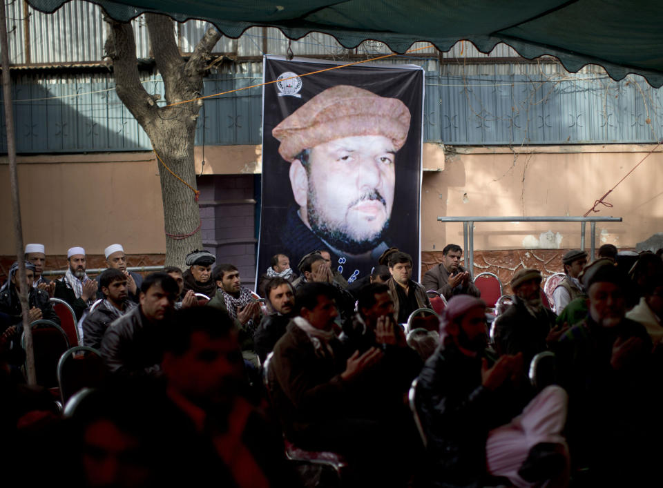 Mourners gather under a giant picture of late Afghan Vice President Field Marshal Mohammed Qasim Fahim outside his house in Kabul, Afghanistan, Monday, March 10, 2014. Afghanistan's influential Vice President Fahim, a leading commander in the alliance that fought the Taliban who was later accused with other warlords of targeting civilian areas during the country's civil war, died March 9, 2014. He was 57. (AP Photo/Anja Niedringhaus)