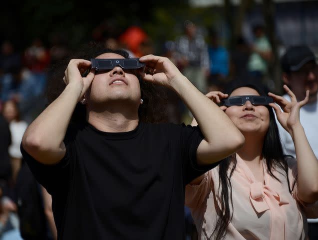 <p>Carlos Tischler/ Eyepix Group/Future Publishing via Getty</p> People look at the solar eclipse with protective glasses.