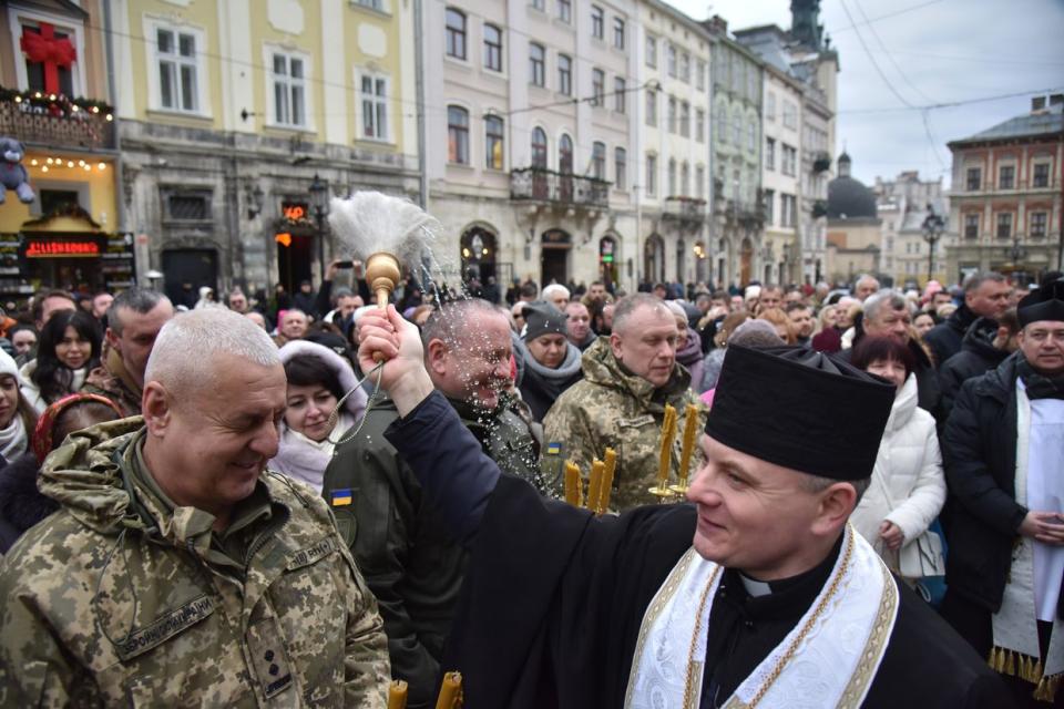 An Orthodox Church of Ukraine priest sprinkles people with holy water during an Epiphany celebration in Lviv, Ukraine, on Jan. 6, 2024. (Pavlo Palamarchuk/Anadolu/Getty Images)