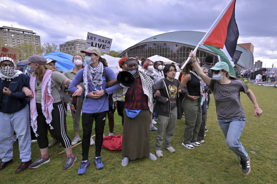 A demonstrator carries a Palestinian flag beside a line of demonstrators Monday, May 6, 2024, in at MIT in Cambridge, Mass. after several hundred demonstrators crossed torn down barricades and joined pro-Palestinian demonstrators that been given a deadline to leave the encampment. (AP Photo/Josh Reynolds)