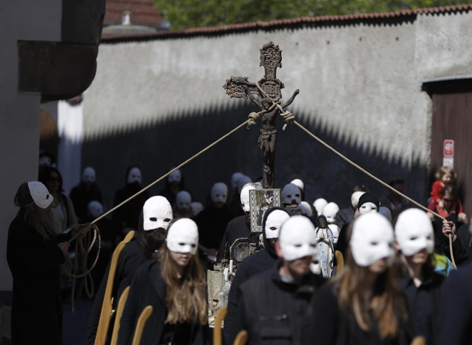 Participants dressed in black, wearing masks, beating drums and pushing small carts that make a synchronized and loud sound take part in an Easter procession through the streets of Ceske Budejovice, Czech Republic, Friday, April 19, 2019. (AP Photo/Petr David Josek)