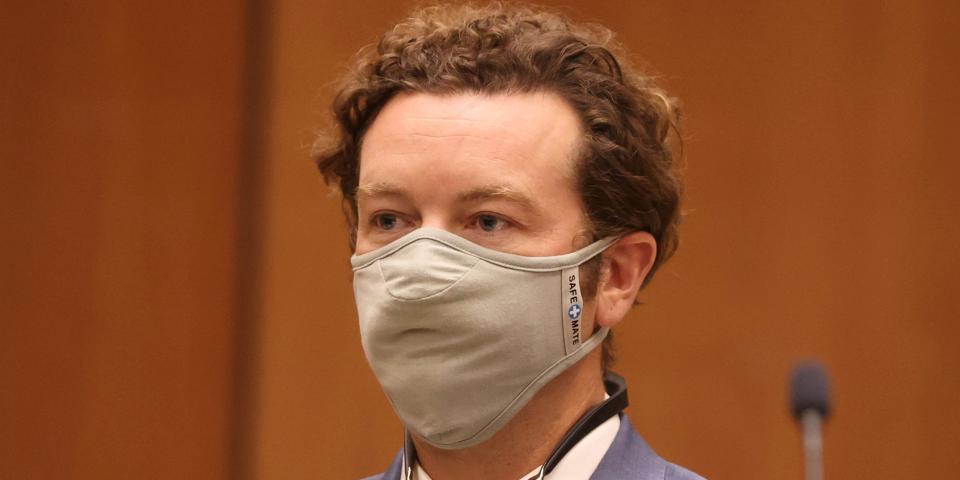 Danny Masterson stands in court with a mask on his face.