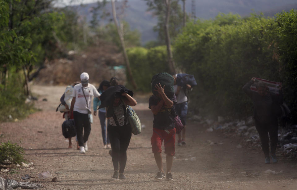 In this Aug. 31, 2018 photo, Venezuelans illegally cross from Venezuela into Colombia, to Villa del Rosario, along a path known as a "trocha." Some Venezuelans cannot cross through an official checkpoint because they lack the proper documents, such as a passport, so they instead traverse illegal dirt road crossings ruled by armed criminals dressed in green fatigues. (AP Photo/Ariana Cubillos)