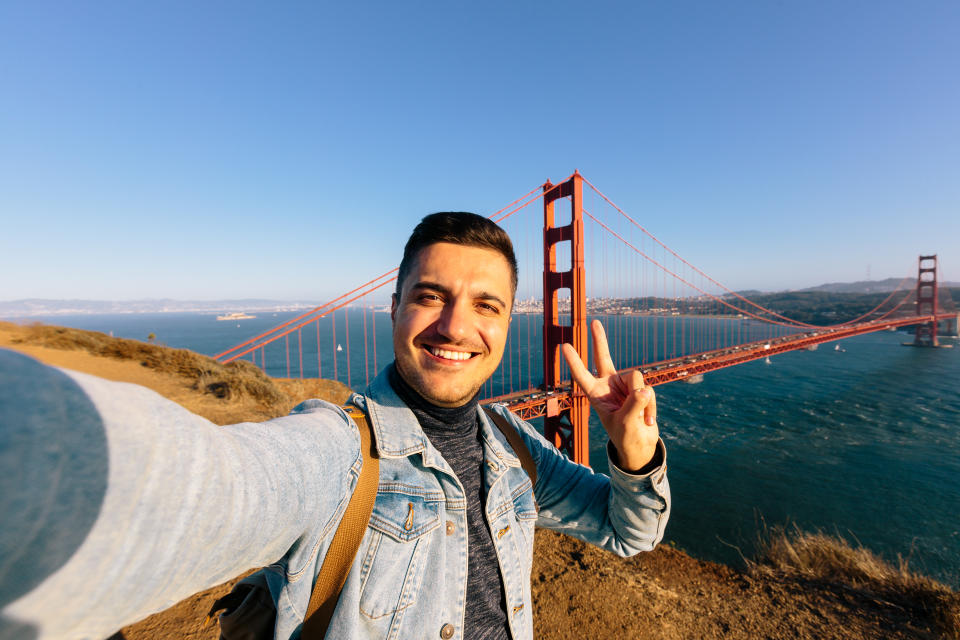 Young smiling happy man taking selfie at Golden Gate Bridge in San Francisco, California, USA