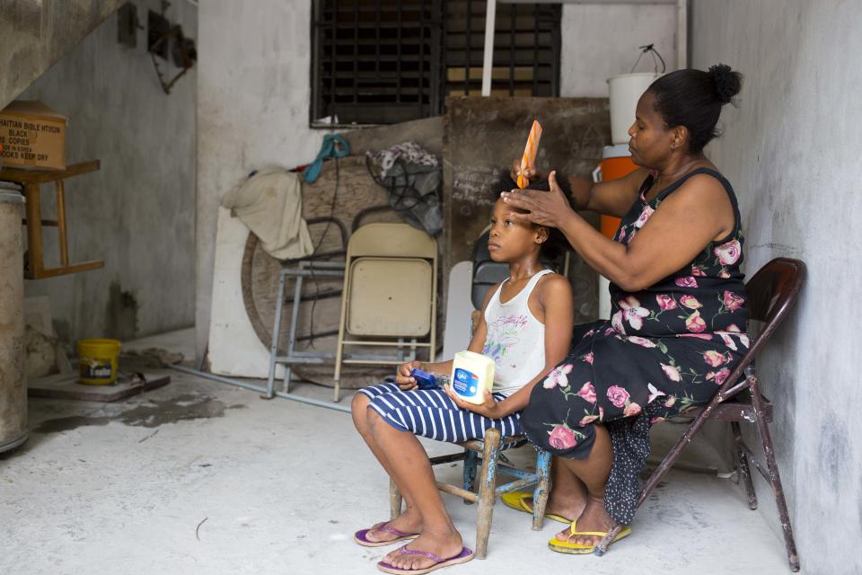 Franchina 11, gets her hair combed by her foster mother Nelia Pierre in their home in Port-au-Prince, Haiti on Saturday, June 30, 2018. The Pierres taught her how to read within weeks of her arrival at their home. "It's like removing the darkness from the eyes of a child," Jeannes Pierre says. (AP Photo/Dieu Nalio Chery)