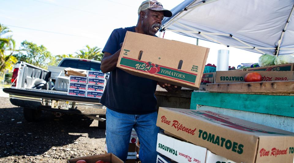 James Stewart, the owner of a long standing produce stand in Harlem Heights, sells tomatoes to a customer on Monday, The stand was destroyed in Hurricane Ian. He rebuilt a small stand that has a tent over it. A GoFundMe has been set up by community member to help rebuild his stand. He wants to have enough space under the roof to provide cover for kids waiting at the corner bus stop.