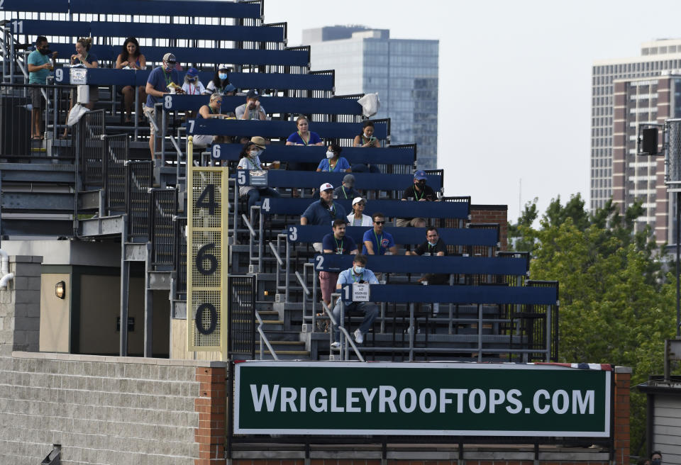 Fans watch from the rooftops an opening day baseball game between the Chicago Cubs and the Milwaukee Brewers, Friday, July, 24, 2020, in Chicago. (AP Photo/David Banks)