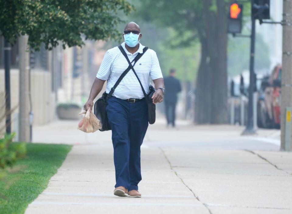 Tony Smith, who works for the City of Milwaukee, uses a mask to protect himself from the Canada wildfire smoke as he heads to work at the Frank P. Zeidler Municipal Building on North Broadway in Milwaukee on Wednesday, June 28, 2023. The quality of Wisconsin's unhealthy air from Canadian wildfires continues.