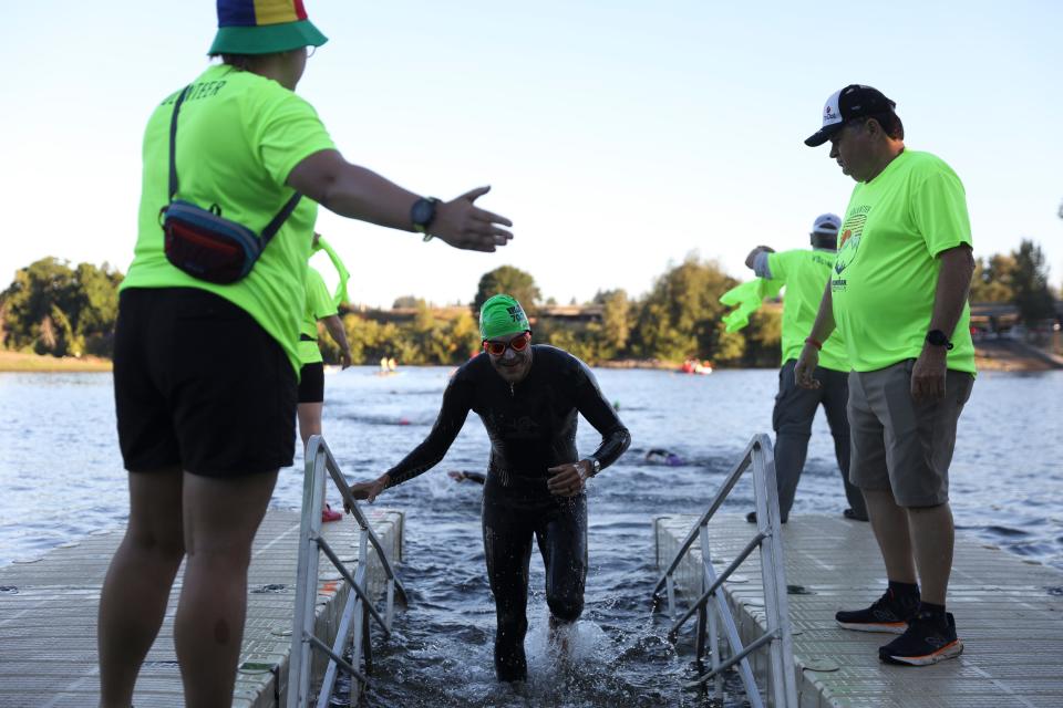 Volunteers cheer on athletes as they come out of the water after swimming 1.2 miles down river in the Willamette River in the Ironman 70.3 Oregon.