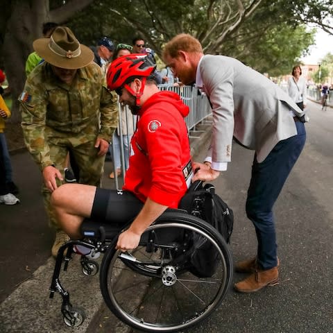 Prince Harry helps a competitor up a walkway - Credit: Reuters