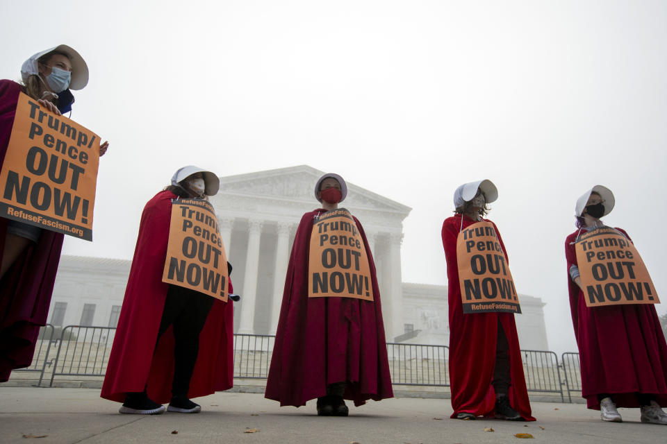 Activists opposed to the confirmation of President Donald Trump's Supreme Court nominee, Judge Amy Coney Barrett, dressed as characters from "The Handmaid's Tale," protest at the Supreme Court on a foggy day, Thursday, Oct. 22, 2020 in Washington. (AP Photo/Jose Luis Magana)