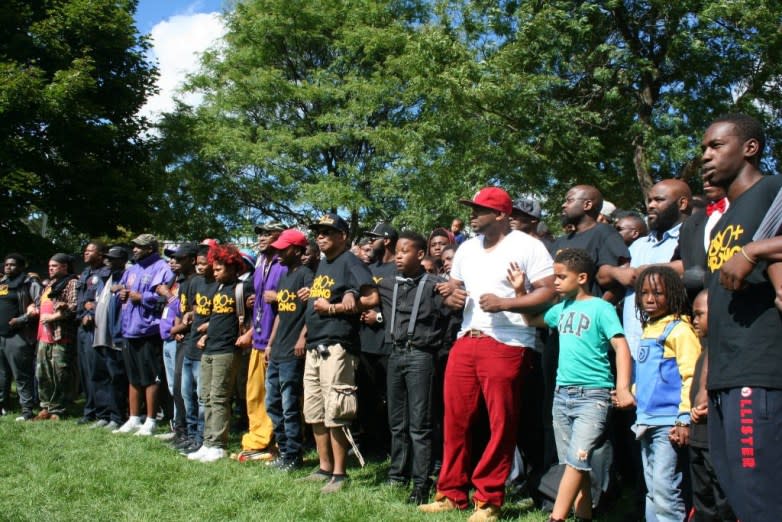 Black men and boys lock arms at a park.