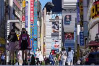 FILE - In this Sept. 20, 2021, file photo, people wearing face masks to help protect against COVID-19 walk past a crossing in Shinjuku, an entertainment district of Tokyo. Japan’s government announced Tuesday, Sept. 28, 2021, the coronavirus state of emergency will end Thursday so the economy can be reactivated as infections slow. (AP Photo/Kiichiro Sato, File)