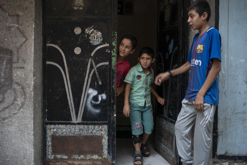 In this Sept. 16, 2018, photo, 8-year-old Mohamed al-Dalo, center, who was shot in the leg during a demonstration, stands at the entrance of his house in Gaza City. Ever since Hamas launched demonstrations in March against Israel's blockade of Gaza, children have been a constant presence in the crowds. Since then, U.N. figures show that 948 children under 18 have been shot by Israeli forces and 2,295 have been hospitalized, including 17 who have had a limb amputated. (AP Photo/Felipe Dana)