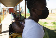 FILE - A woman with a child on her back waits in a queue to be screened for COVID-19 at a testing centre in Soweto, South Africa, Wednesday, May 11, 2022. French President Emmanuel Macron is joining several African leaders on Thursday June 20, 2024 to kick off a planned $1 billion project to accelerate the rollout of vaccines in Africa, after the coronavirus pandemic exposed gaping inequalities in access to them. (AP Photo/Denis Farrell, File)