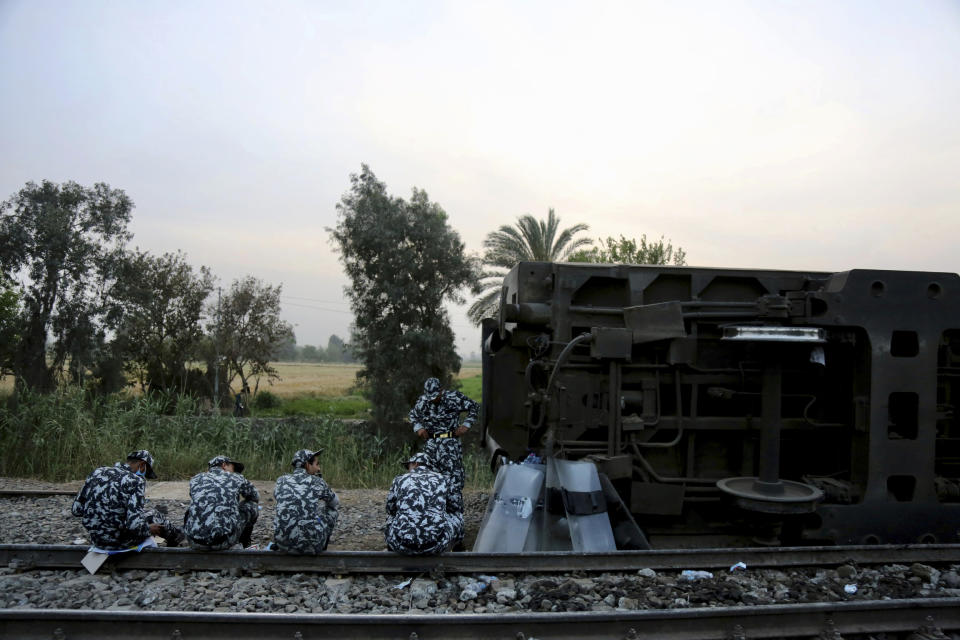 Egyptian security forces prepare to break their fast during the holy month of Ramadan, at the site of a passenger train that derailed injuring around 100 people, near Banha, Qalyubia province, Egypt, Sunday, April 18, 2021. The train was travelling to the Nile Delta city of Mansoura from the Egyptian capital, the statement said. (AP Photo/Fadel Dawood)