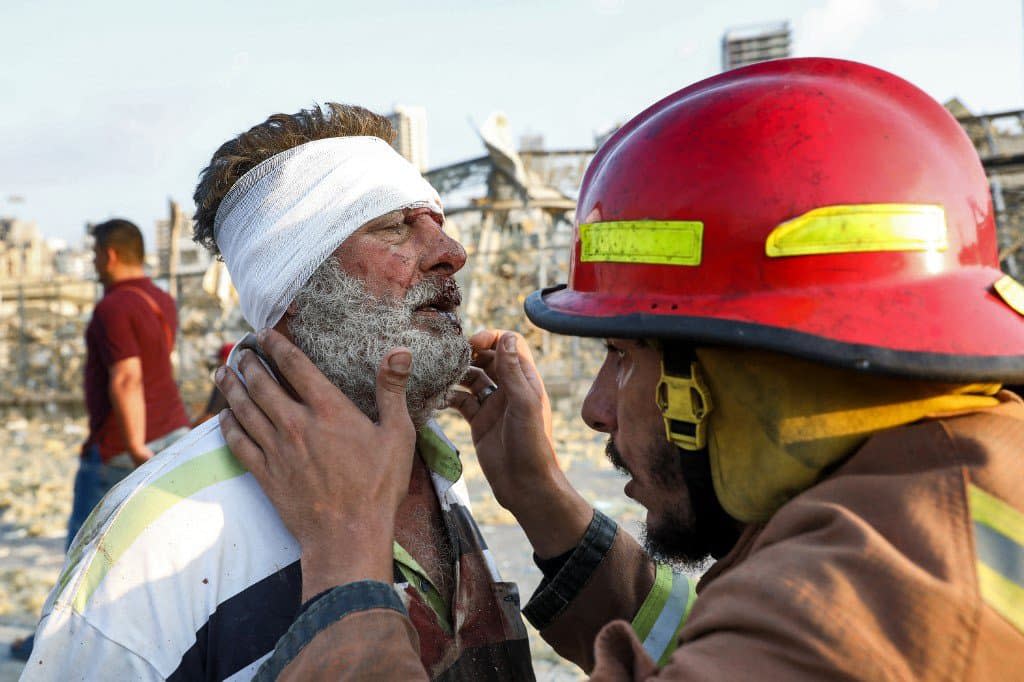 Un pompier portant secours à un homme blessé après les explosions survenues à Beyrouth. - Anwar Amro