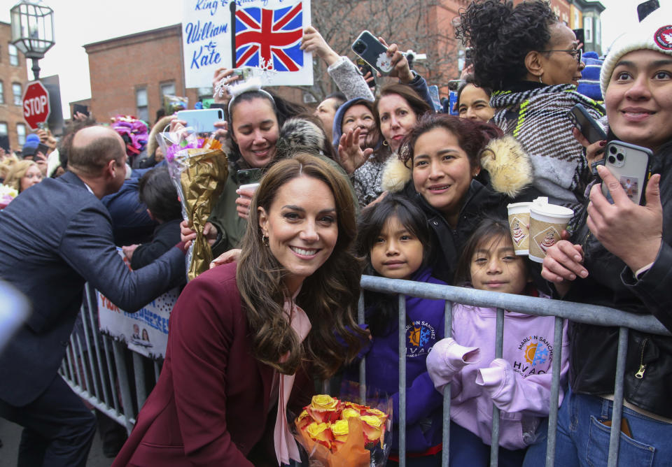 Britain's Kate, Princess of Wales poses for a photo with the crowd after a tour of Roca Thursday, Dec. 1, 2022, in Chelsea, Mass. Britain's Prince William greets people on the left. (AP Photo/Reba Saldanha, Pool)