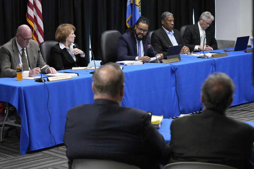 Oklahoma Pardon and Parole Board chairman Scott Williams, center, talks with attorneys for Scott Eizember, foreground, during a clemency hearing for Eizember, Wednesday, Dec. 7, 2022, in Oklahoma City. Eizember was convicted in the shotgun slayings of AJ and Patsy Cantrell in 2003. The five-member board voted 3-2 to reject clemency for Eizember, 61, who is scheduled to receive a lethal injection on Jan. 12 at the Oklahoma State Penitentiary in McAlester. (AP Photo/Sue Ogrocki)