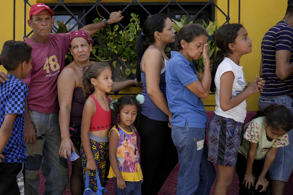 Local residents line up for aid in Las Tejerias, Venezuela, Wednesday, Oct. 12, 2022, four days after it was hit by a landslide caused by heavy rains that killed dozens. (AP Photo/Matias Delacroix)