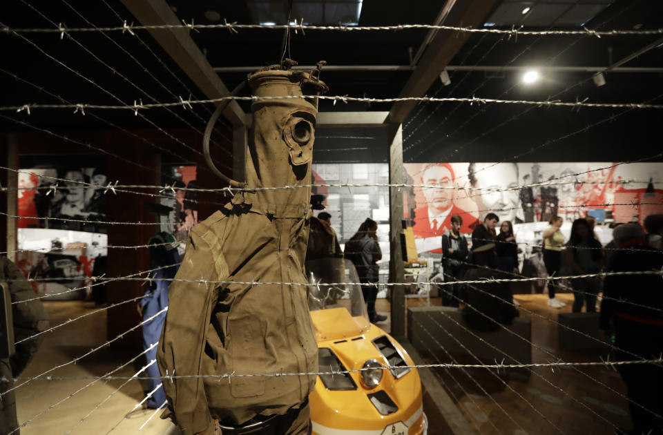 In this picture taken on Tuesday, Nov. 12, 2019, visitors view the exhibition "The Technology in Dictatorships," at the National technical Museum in Prague, Czech Republic. The exhibition, the first of that kind here, marks the 30th anniversary of the 1989 anti-communist Velvet Revolution by looking back at the surreal repression of a nation and resistance against it. (AP Photo/Petr David Josek)