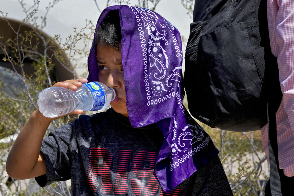 A young child with his family claiming to be from Guatemala, cools down with a wet bandana and a bottle of water while waiting to be picked up by U.S. Customs and Border Patrol, Tuesday, Aug. 29, 2023, in Organ Pipe Cactus National Monument near Lukeville, Ariz. The Border Patrol's Tucson Sector in July suddenly became the busiest along the U.S-Mexico border for the first time since 2008. The area has seen migrants from faraway countries like Pakistan and China, as well as Mauritania, where social media is drawing young people to a new route that goes through Nicaragua. There are also large numbers of people from Ecuador. (AP Photo/Matt York)