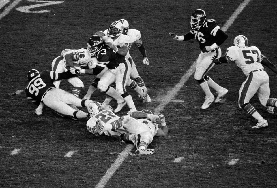 Jets defensive lineman Mark Gastineau (99) and Joe Klecko, right, sack Dolphins quarterback David Woodley in the second half of a 16-15 win over Miami at New York's Shea Stadium, Nov. 23, 1981.