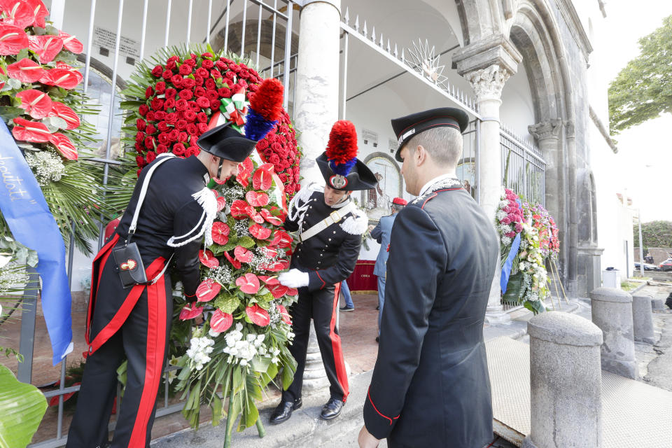 Carabinieri officers hold a floral wreath in front of the Santa Croce church where the funeral of Carabinieri officer Mario Cerciello Rega will be held, in Somma Vesuviana, southern Italy, Monday, July 29, 2019. In a statement Saturday, Carabinieri officers investigating the death of Cerciello Rega, 35, said two young American tourists have been detained for alleged murder and attempted extortion. (AP Photo/Andrew Medichini)