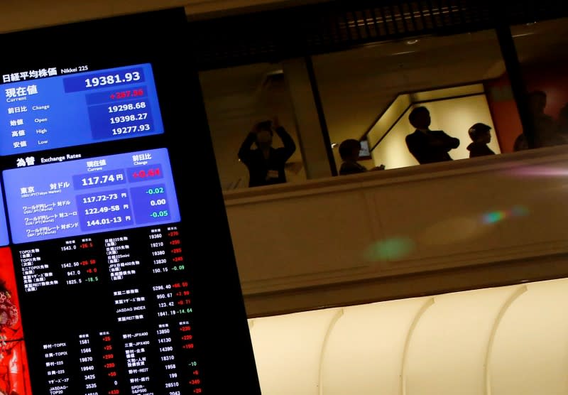 People are seen behind an electronic board showing stock prices after the New Year opening ceremony at the Tokyo Stock Exchange (TSE), held to wish for the success of Japan's stock market, in Tokyo, Japan, January 4, 2017. REUTERS/Kim Kyung-Hoon