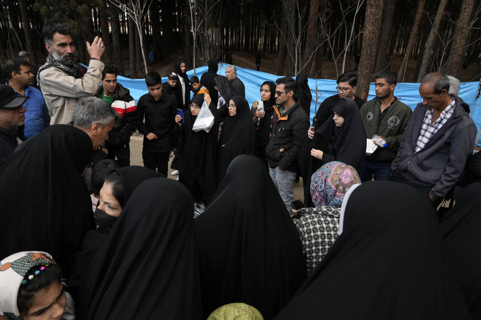 A man speaks for people as they visit the scene of Wednesday's bomb explosion in the city of Kerman, 820 km (about 510 miles) southeast of Tehran, Iran, Thursday, Jan. 4, 2024. Investigators believe suicide bombers likely carried out an attack on a commemoration for an Iranian general slain in a 2020 U.S. drone strike, state media reported Thursday, as Iran grappled with its worst mass-casualty attack in decades and as the wider Mideast remains on edge. (AP Photo/Vahid Salemi)