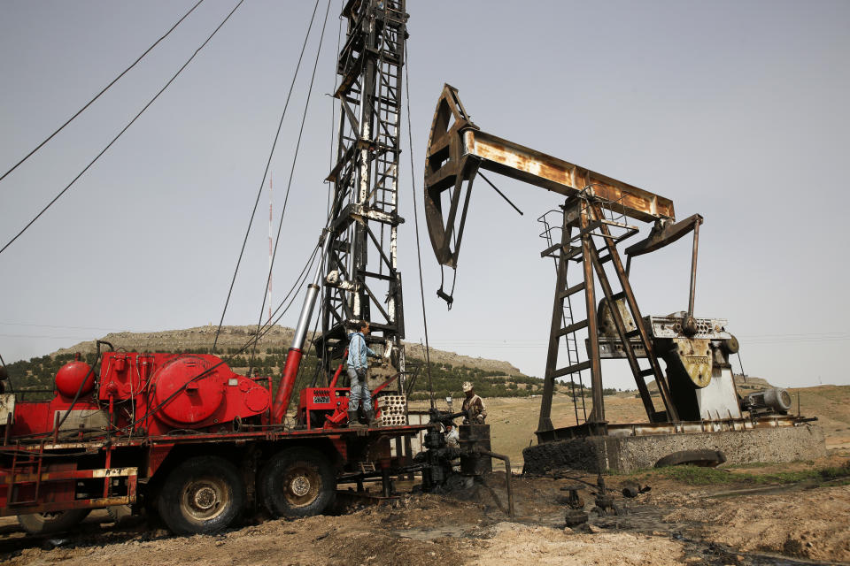 FILE - This March 27, 2018 file photo shows Syrian workers fixing pipes of an oil well at an oil field controlled by a U.S-backed Kurdish group, in Rmeilan, Hassakeh province, Syria. President Donald Trump's decision to dispatch new U.S. forces to eastern Syria to secure oil fields is being criticized by some experts as ill-defined and ambiguous. But the residents of the area, one of the country's most remote and richest regions, hope the U.S. focus on eastern Syria would bring an economic boon and eliminate what remains of the Islamic State group. (AP Photo/Hussein Malla, File)